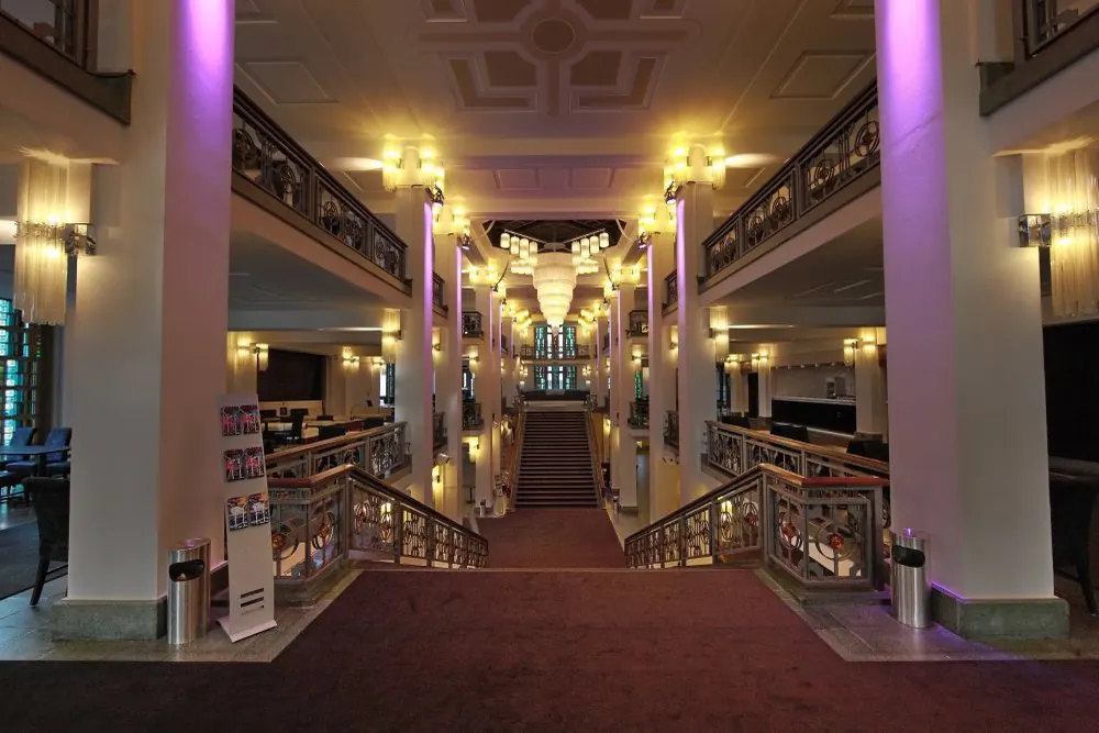 A broad foyer with tall columns, a staircase and a chandelier in a Berlin revue theatre